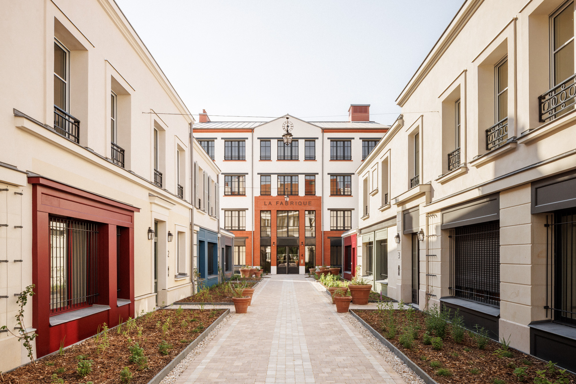 Vue de la Cour des Artisans menant au bâtiment « La Fabrique » dans un ensemble de 47 logements sociaux à Serris (Seine-et-Marne), conçu par Cussac Architectes.